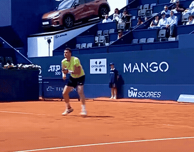 Man In Yellow Shirt Playing Tennis In Front Of Mango Sign GIF