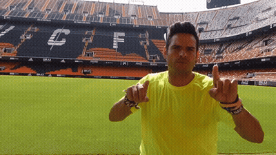 Man In Yellow Shirt Pointing At Stadium GIF