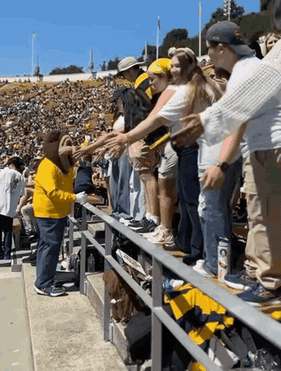 Man In Yellow Shirt Shaking Hands With Woman In Crowd GIF