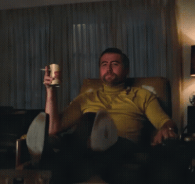 Man In Yellow Shirt Sitting Holding Mug Pointing GIF
