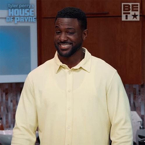 Man In Yellow Shirt Smiling In Front Of House Of Payne Sign GIF