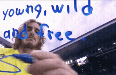 Man in Yellow Shirt Writes Young Wild and Free in Blue Marker