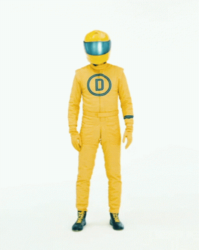 Man in Yellow Suit and Helmet in Front of Here Sign
