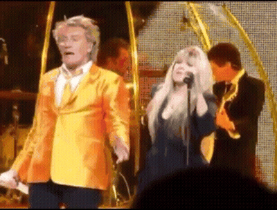 Man In Yellow Suit Next To Woman Singing GIF