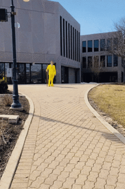Man In Yellow Suit Walking Down Brick Walkway GIF