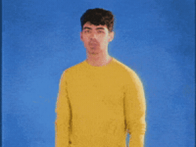 Man In Yellow Sweater Against Blue Background GIF