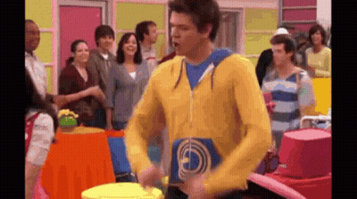 Man In Yellow Sweatshirt Playing Drum In Front Of Crowd GIF