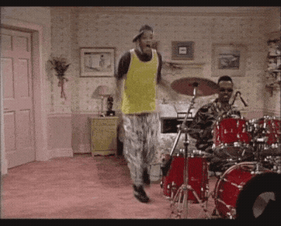 Man In Yellow Tank Top Dancing In Front Of Drum Set GIF
