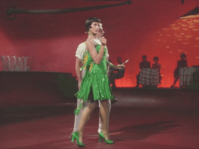 Man In Yellow Vest And Woman In Green Dress Dancing GIF