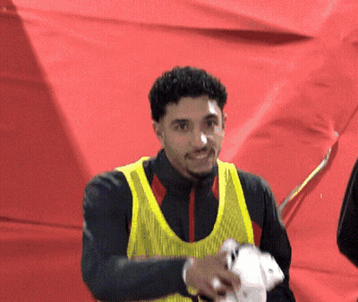 Man In Yellow Vest In Front Of Red Wall GIF