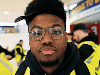 Man In Yellow Vest Looking At Camera GIF