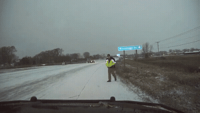 Man In Yellow Vest On Snowy Road Near Winterhage Dr Sign GIF