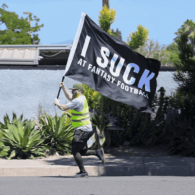 Man In Yellow Vest Running With I Suck At Fantasy Football Flag GIF