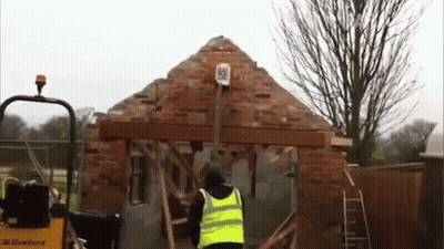 Man In Yellow Vest Standing Before Construction GIF