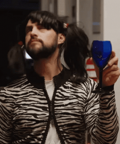 Man In Zebra Print Sweater Holding Blue Glass GIF