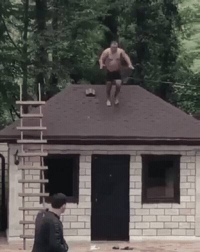 Man Jumping Off Brick Building Roof GIF