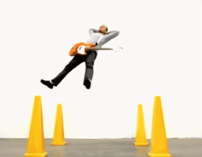Man Jumping Over Yellow Cones Holding Pumpkin GIF