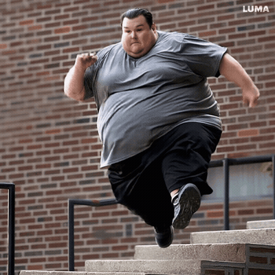 Man Jumping Up Stairs In Front Of Brick Building GIF