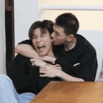 Man Kissing Another Man On Neck At Table GIF