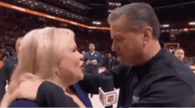 Man Kissing Woman On Cheek In Basketball Stadium GIF