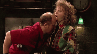 Man Kissing Woman On Cheek In Front Of Clock 2:01 GIF
