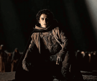 Man Kneeling In Dark Wearing Cape GIF