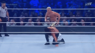 Man Kneeling In Wrestling Ring With Another Man Standing Over Him GIF