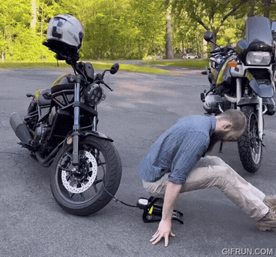 Man Kneeling Next To Motorcycle With Helmet GIF