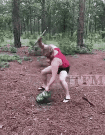 Man Kneeling Next To Smoking Watermelon In Woods GIF