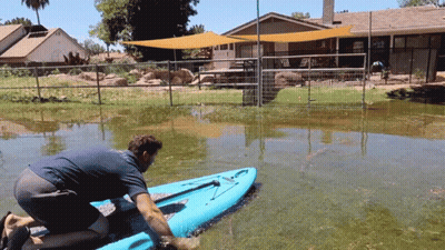 Man Kneeling On Blue Kayak In Flooded Area GIF