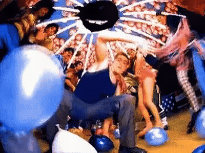 Man Kneeling On Bowling Alley Surrounded By Balloons GIF