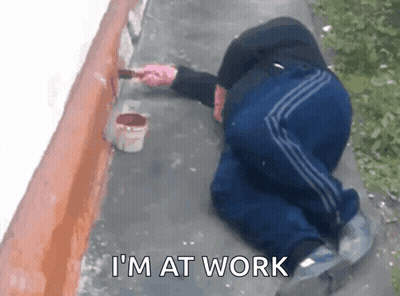 Man Kneeling Painting Wall Saying I'm At Work GIF