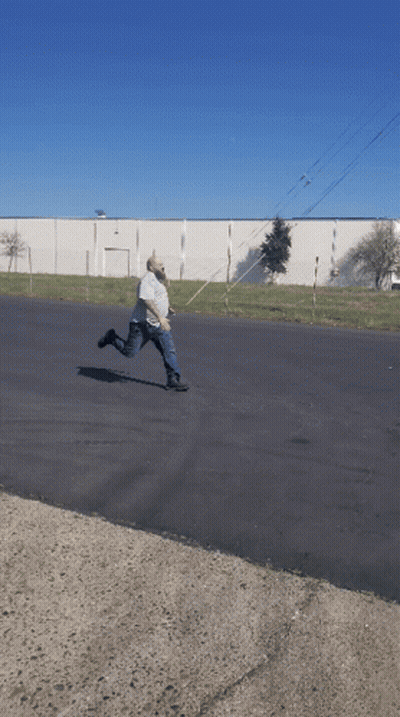 Man Kneeling While Another Man Rides Scooter GIF