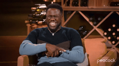 Man Laughing In Chair In Front Of Wine Shelf GIF