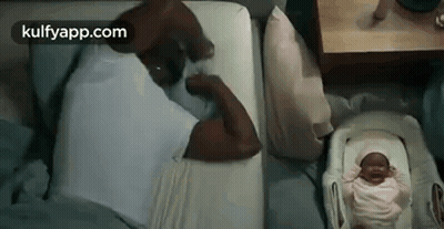Man Laying In Bed Beside Baby In Crib GIF