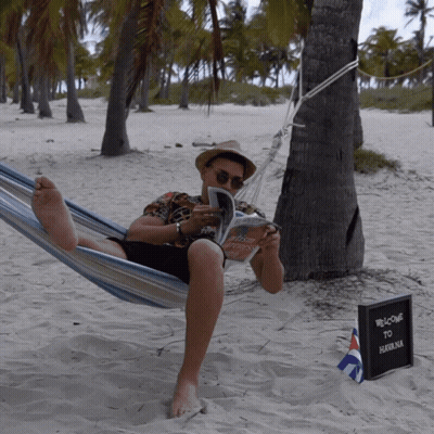 Man Laying In Hammock Reading Book Next To Welcome To Salomon Sign GIF