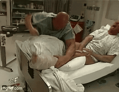 Man Laying In Hospital Bed With Another Man Standing Over Him GIF