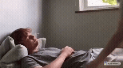 Man Laying On Bed Arms Outstretched By Window GIF
