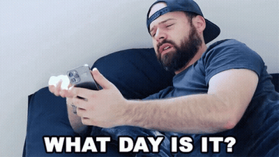 Man Laying On Bed Looking At Phone Saying What Day Is It GIF