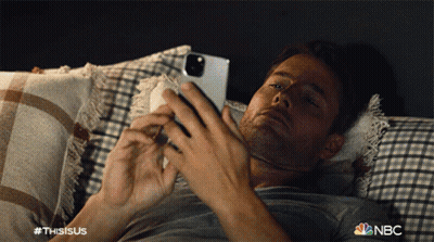 Man Laying On Bed Looking At Phone With NBC Logo GIF