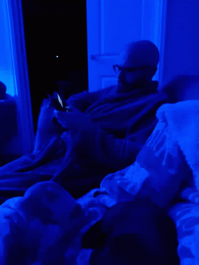 Man Laying on Bed With Blue Light and Mickey Blanket