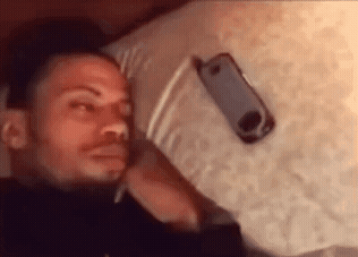 Man Laying On Bed With Cell Phone On Head GIF