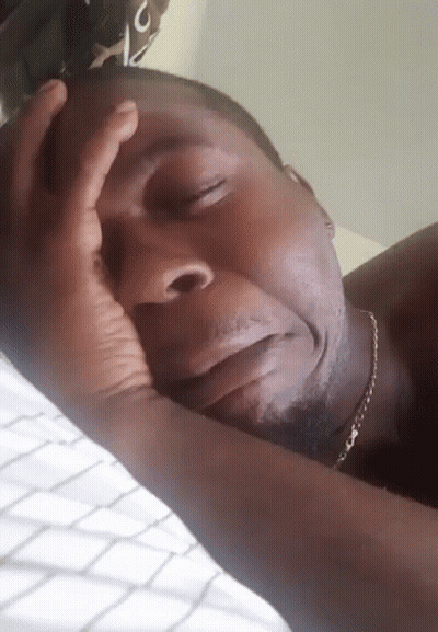 Man Laying On Bed With Hand On Head GIF