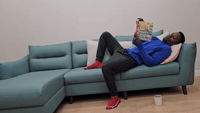 Man Laying On Blue Couch Reading Bobs GIF