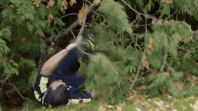 Man Laying On Ground Holding Tree Branch In Woods GIF