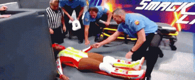 Man Laying On Stretcher In Front Of Smackdown Sign GIF