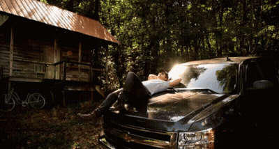 Man Laying On Truck Hood In Woods GIF