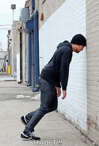 Man Leaning Against Brick Wall Saying Hault GIF