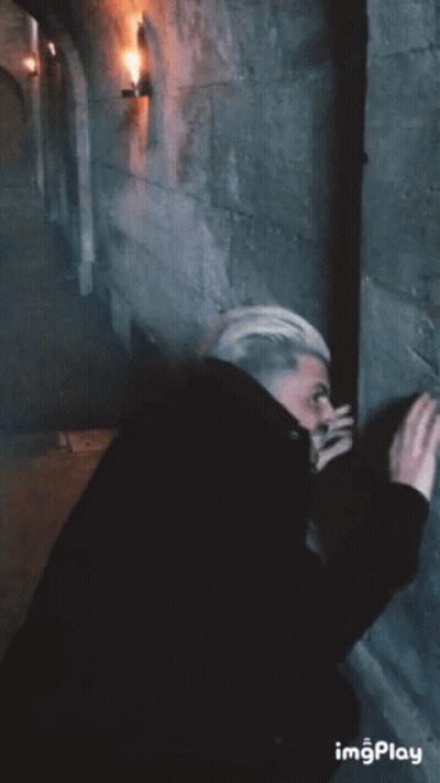 Man Leaning Against Stone Wall In Dark Room GIF