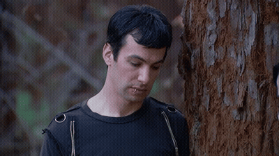 Man Leaning Against Tree In Black Shirt Saying Okay GIF